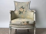 an old chair with a floral upholstered back and arms