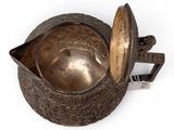 an old metal bowl with a lid sitting on top of a white surface