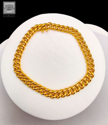 gold plated chain bracelet on a white plate with a black background