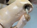 a person holding a wooden doll with a toothbrush in it ' s mouth