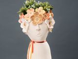 a white vase with flowers in the shape of a head