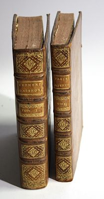 two old books are sitting side by side on a white surface