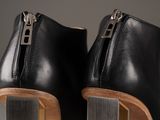 the heel of a pair of black leather boots with a wooden heel