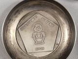 a silver plate with a coin on it and a coin in the background