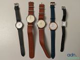four watches are lined up in a row on a table