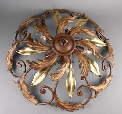 une décoration murale en métal ornée de feuilles dorées et d'un bouton marron