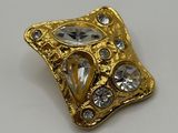 a close up of a gold and crystal broochle on a white surface