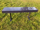 une console noire posée dans l'herbe, avec un arbre en arrière-plan