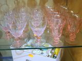 une étagère en verre sur laquelle sont posés des verres à vin roses