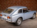 an image of a silver car parked in front of a brick wall