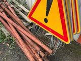un tas de tuyaux rouillés à côté d'un panneau d'avertissement jaune et rouge