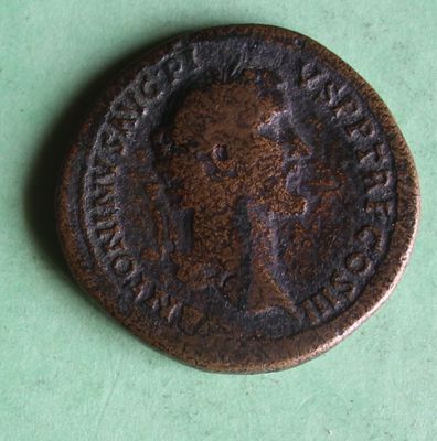 an old coin with a man on it on a green surface