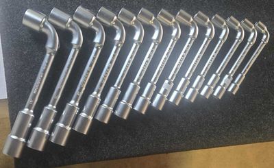 six wrenches that are lined up on a black surface