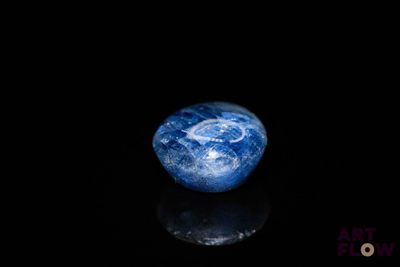 une image représentant une bille bleue et blanche posée sur une surface noire