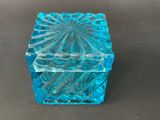 a small blue glass box on a black surface