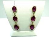 pair of gold tone earrings with purple stones on display