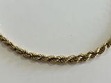 a close up of a gold rope necklace on a white surface