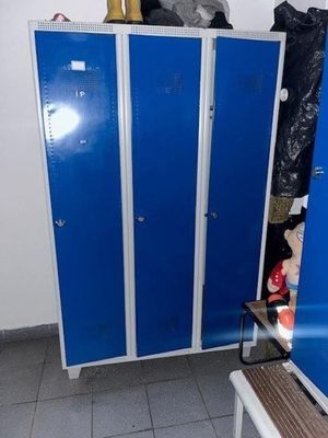 two blue lockers in the corner of a room next to a table