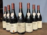 six bottles of wine are lined up on a wooden table