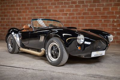 an image of a black sports car parked in front of a brick wall