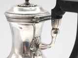 a silver tea pot with a handle on a table