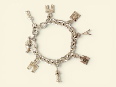 a silver bracelet with charms on it on a white surface