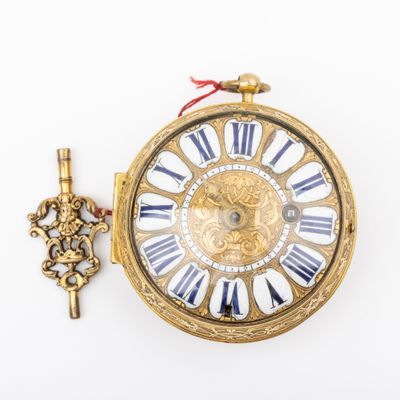 a gold clock with roman numerals and a key
