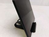 a black tablet computer sitting on a stand on a white surface