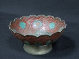 a red and green bowl on a stand on a black background