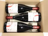 three bottles of wine in a cardboard box on a table