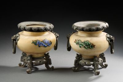 une paire de vases ornés d'anses en forme de dragon, posés sur des socles, sur fond gris