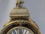 a gold clock with a statue on top of it