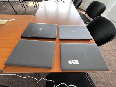 quatre ordinateurs portables posés sur une table dans une salle de réunion
