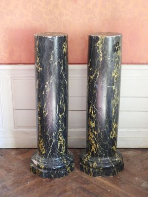 pair of black and gold marble pedestals on a wooden floor