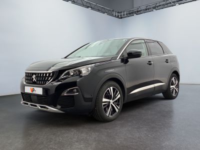 La voiture noire est garée dans une grande pièce aux murs blancs.