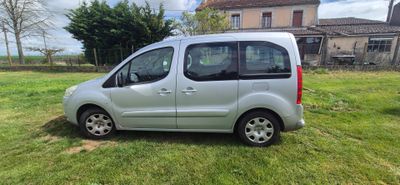 La petite camionnette argentée est garée sur la pelouse devant une maison.