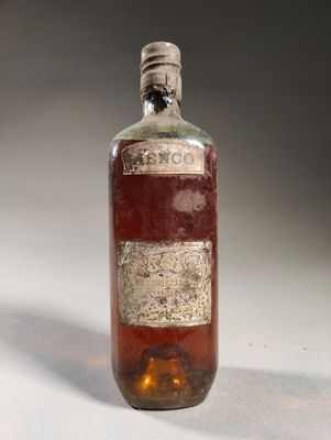 une vieille bouteille d'alcool posée sur une table blanche