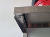a red pan sitting on a shelf next to a black pan