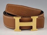 ceinture en cuir marron avec une boucle en forme de H dorée sur fond blanc