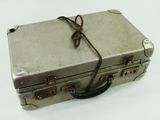 une valise argentée posée sur une surface blanche