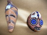two masks that are sitting on a leather surface
