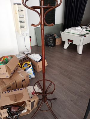 un porte-manteau marron dans une pièce où se trouvent des cartons et un billard
