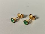 a pair of gold earrings with emerald stones