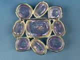 a close up of a purple stone broochle on a blue surface