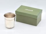 a silver cup sitting next to a box on a table
