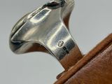 a silver ring with a diamond on it sitting on a piece of leather