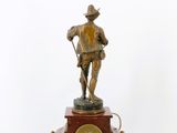 bronze figurine of a man with a clock on a wooden base