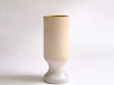 a white vase with a yellow rim sitting on a white surface