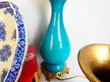a blue vase sitting on a table next to a gold bowl