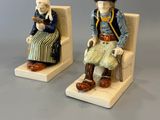 deux figurines représentant des personnes assises sur des chaises, posées sur une surface grise